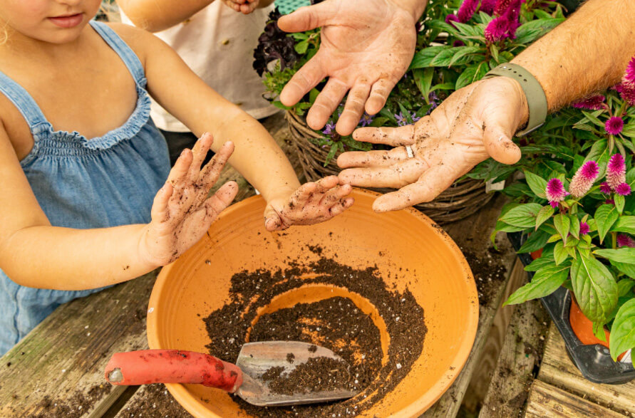 A child and adult looking at potting soil.