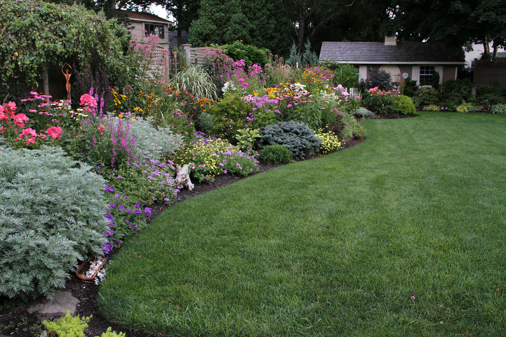 A mowed lawn and garden of shrubs.