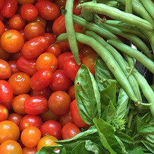 Cherry tomatoes, herbs, and string beans side-by-side.